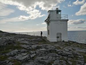 a man standing next to a lighthouse on the rocks at Puffin rooms in Lisdoonvarna