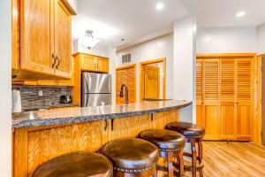 a kitchen with wooden cabinets and bar stools at Deer Valley Courchevel Condo in Park City