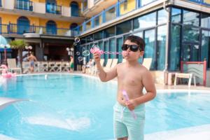 a young man playing with bubbles in a swimming pool at Hotel Brioni Mare in Lido di Jesolo +65 photos