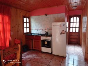 a kitchen with a white refrigerator and a stove at Ma-Ri Cabañas y Camping in Puerto Iguazú