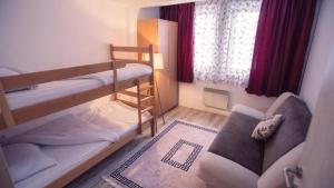 a small room with bunk beds and a couch at Aber Apartmani Kopaonik in Kopaonik