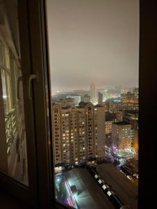 uma vista de uma janela de uma cidade à noite em View Apartments, 22 floor with 2 rooms em Kiev