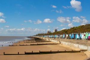 a row of colourful beach huts on a beach at Gulliver's Cottage in Frinton-On-Sea in Frinton-on-Sea