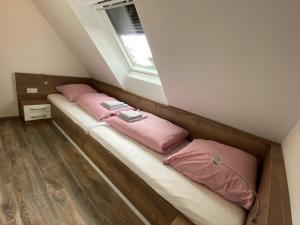 a room with two beds with pink pillows on them at Ferienhaus Seestern am Harkebrügger See mit Sauna und Kamin in Barßel