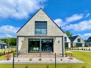 a brick house with a gambrel roof at Ferienhaus Seestern am Harkebrügger See mit Sauna und Kamin in Barßel