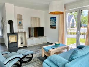 ein Wohnzimmer mit 2 blauen Sofas und einem TV in der Unterkunft Ferienhaus Seestern am Harkebrügger See mit Sauna und Kamin in Barßel