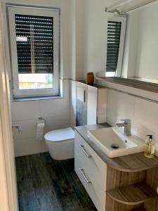 a white bathroom with a toilet and a sink at Ferienhaus Seestern am Harkebrügger See mit Sauna und Kamin in Barßel +10 photos