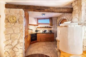 a kitchen with a stone wall and a clock on the wall at La pratolina monolocale in Castello di Fiemme