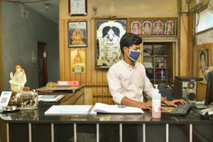 a man wearing a face mask at a desk at Balaji Lodge in Villupuram
