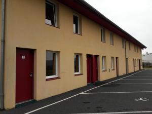 a building with red doors in a parking lot at Libre Hôtel in La Vespière