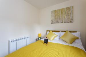 um quarto com uma cama amarela com almofadas amarelas em Luxury Burgess Apartments close to Soton General Hospital em Southampton