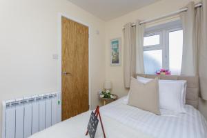 a bedroom with a bed with white sheets and a window at Luxury Burgess Apartments close to Soton General Hospital in Southampton