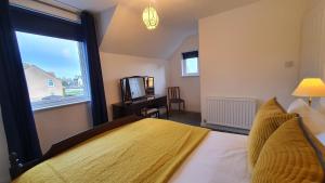 a bedroom with a bed with a yellow bedspread and a window at 51 Milton Crescent in Anstruther