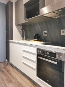 a kitchen with white cabinets and a black oven at Menlyn Residence - Luxury Six Sleeper in Pretoria