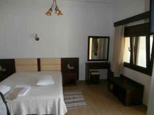 a bedroom with a white bed and a mirror at Villa Barouti in Kinira