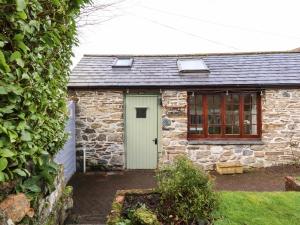 a stone cottage with a green door and windows at Little Orchard Barn in St Austell
