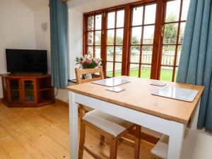 a dining room with a table and a large window at Little Orchard Barn in St Austell