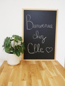 Una pizarra con un cartel que dice que el banquete deja caer una vida y una planta en Studio cosy Bienvenue chez Elle en Saint-Denis-de lʼHôtel