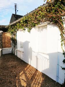 a white garage with an ivy covered fence at Studio cosy Bienvenue chez Elle in Saint-Denis-de lʼHôtel