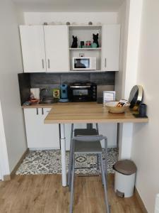 cocina con mesa de madera y microondas en Studio cosy - proche gare & centre-ville - stationnement - cour intérieure table & chaises, en Saint-Brieuc