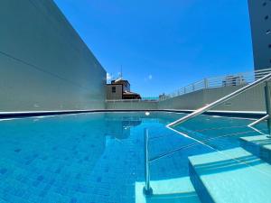 a swimming pool with blue tiles on the side of a building at Flat Unitá Homestay in Praia Grande