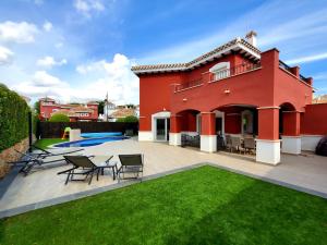 a red house with a patio and a yard at VILLA PALMITO Mar Menor Golf in Torre-Pacheco