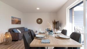 ein Esszimmer mit Tisch und Couch in der Unterkunft Ferienhaus Sonneneck am Harkebrügger See mit Sauna in Barßel + 25 Fotos