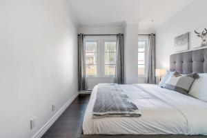 a white bedroom with a large bed and two windows at INITIAL - MOOSE - Chutes-Montmorency in Boischâtel