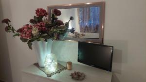 een tv zittend op een tafel met een vaas met bloemen bij Sweet Home in Lido di Ostia