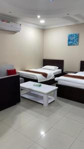 a room with three beds and a coffee table at شقق المربعة للشقق المخدومة in Ruqaiqah