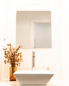 un lavandino in bagno con specchio e un vaso con fiori di A BURGUESA - GUESTHOUSE a Castelo de Vide Altre 40 foto