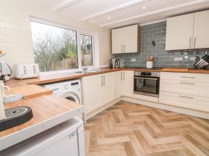 a kitchen with white cabinets and a wooden floor at Kims Cottage in Penzance