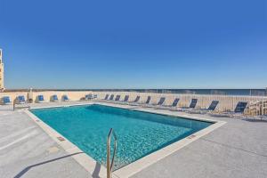 a swimming pool with chairs and the ocean in the background at The Gulf Tower Condos in Gulf Shores