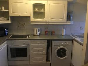 cocina con armarios blancos y lavadora en High View Retreat, en Lewes