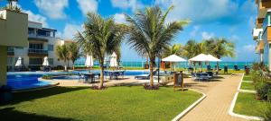 un complexe avec une piscine, des palmiers et l'océan dans l'établissement Flat em Resort Beira Mar na Praia de Búzios - Qavi, à Pirangi do Sul