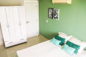 - une chambre avec des murs verts et un lit avec deux oreillers dans l'établissement Flat em Resort Beira Mar na Praia de Búzios - Qavi, à Pirangi do Sul 7 autres photos