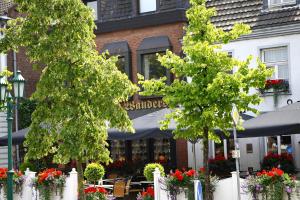 two trees in front of a restaurant with tables and umbrellas at Hotel-Restaurant Wanders in Elten