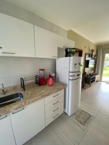 a kitchen with white cabinets and a white refrigerator at Boas Vistas Canoa Quebrada in Aracati