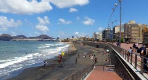 a beach with people on the sand and the ocean at Guanarteme Vista Surf in Las Palmas de Gran Canaria