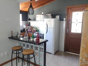a kitchen with a white refrigerator and two bar stools at Casa da Lu Itacoatiara -Apartamento Costão in Niterói