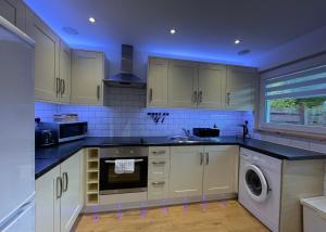 a kitchen with white cabinets and a washer at Blarmore Apartment Inverness in Inverness