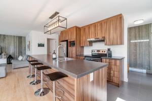 a kitchen with wooden cabinets and a kitchen island with bar stools at INITIAL - KOALA - Mont-Sainte-Anne in Beaupré