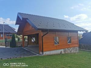un petit bâtiment en bois avec un toit noir dans l'établissement Vila Engelshof - Zlatibor, à Zlatibor