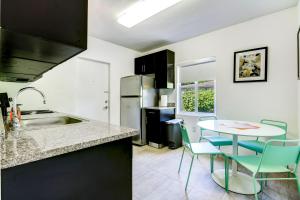 uma cozinha com um lavatório e uma mesa com cadeiras em Cottages El Portal em Miami