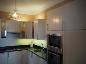 a kitchen with white cabinets and a sink and a microwave at Attico Sulla Spiaggia in Viareggio