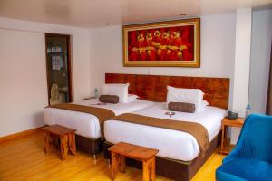 a hotel room with two beds and a painting on the wall at Hotel Tara Machupicchu in Machu Picchu