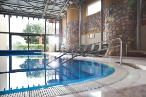 a large swimming pool in a building with a large window at Hotel Makar Sport & Wellness in Pécs
