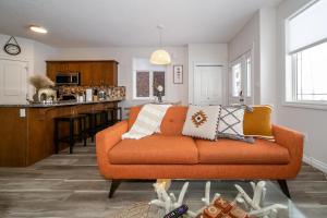 a living room with an orange couch and a kitchen at Bali Style Home - King Bed - Fireplace - Jacuzzi - Fast Wi-Fi - Free Netflix & Garage Parking in Edmonton