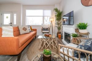 ein orangefarbenes Sofa im Wohnzimmer mit Kamin in der Unterkunft Bali Style Home - King Bed - Fireplace - Jacuzzi - Fast Wi-Fi - Free Netflix & Garage Parking in Edmonton