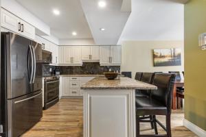 a kitchen with white cabinets and stainless steel appliances at 2BR Slopeside in Chateau Ridge Blue Mountains in Blue Mountains